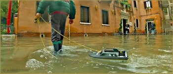 Acqua Alta Venise : Petit Vénitien profitant de l'occasion pour jouer avec son bateau de police devant la caserne des Carabinieri, Campo San Zaccaria, dans le Sestier du Castello à Venise.