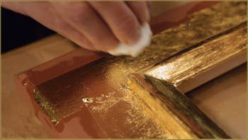 La feuille d'or est ensuite tamponnée avec un coton pour éliminer au maximum la colle sur laquelle elle repose et la faire mieux adhérer au cadre.