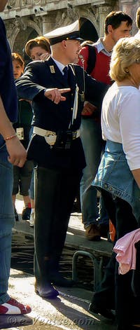 Venezianischer Polizist, der den Fußgängerverkehr auf den Acqua-Alta-Stegen auf dem Markusplatz in Venedig regelt.